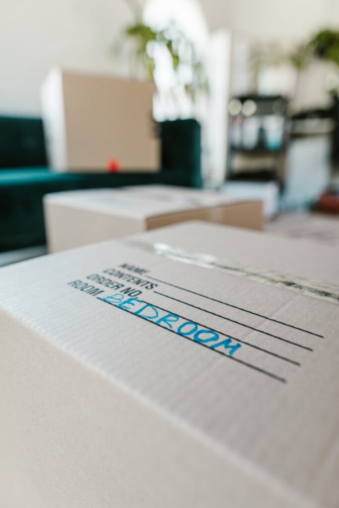 Packed cardboard box labeled 'Bedroom' indoors, ready for moving.